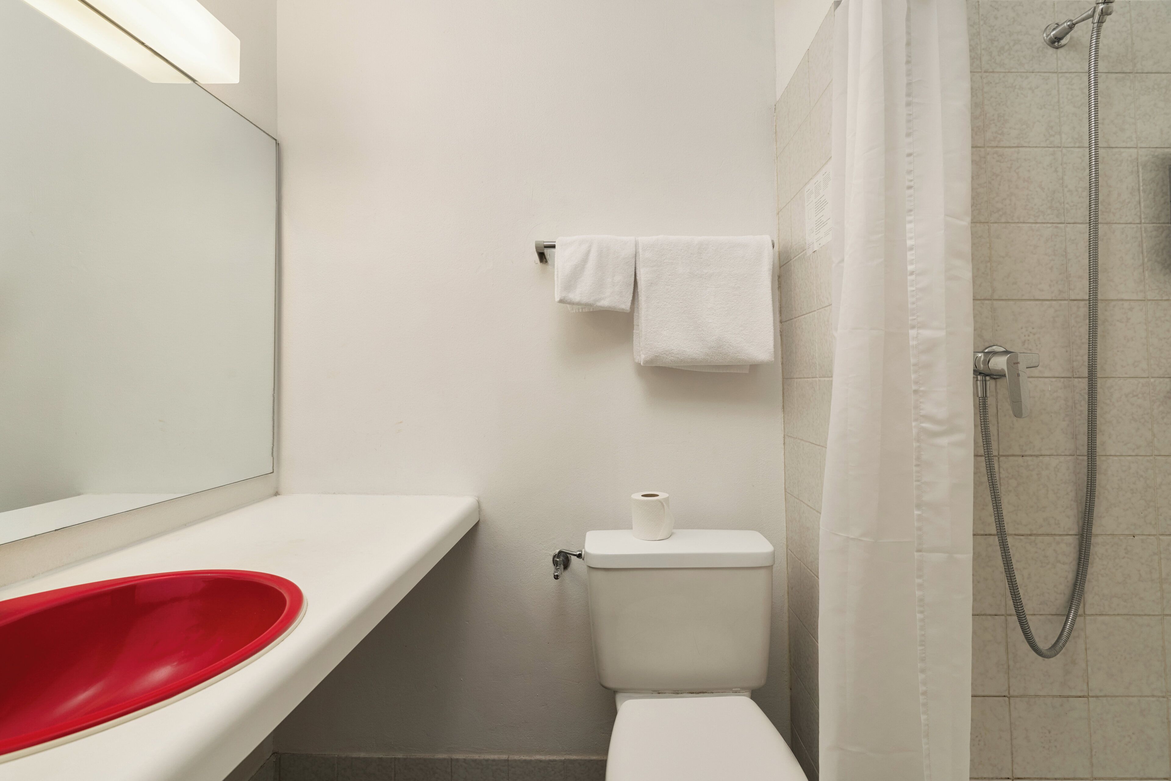 Een badkamer met een wit wastafelmeubel, toilet, douche en spiegel.