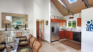 Una cocina moderna con armarios de madera, un refrigerador de acero inoxidable y un comedor con mesa para cuatro.