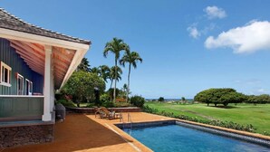 Zona de piscina con vista a un campo de golf y palmeras.