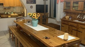 A kitchen with wooden cabinets, a dining table with benches, a ceiling fan, and a TV. - Cottage located along the coastal strip opposite Asinara. (Eden Beach)