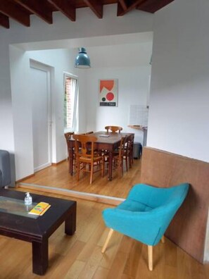 Cozy living space with a dining area, featuring a wooden dining table and chairs, a blue armchair, and a coffee table.