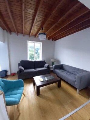 Relax in this spacious living room with a high ceiling, featuring a sofa, armchair, and coffee table.