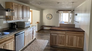 A kitchen with wooden cabinets, a stainless steel sink, a coffee maker, and a microwave. - NEW Entire Cabin, 🏔 & 🌊 Views + Hot Tub Downtown (Grand Lake)