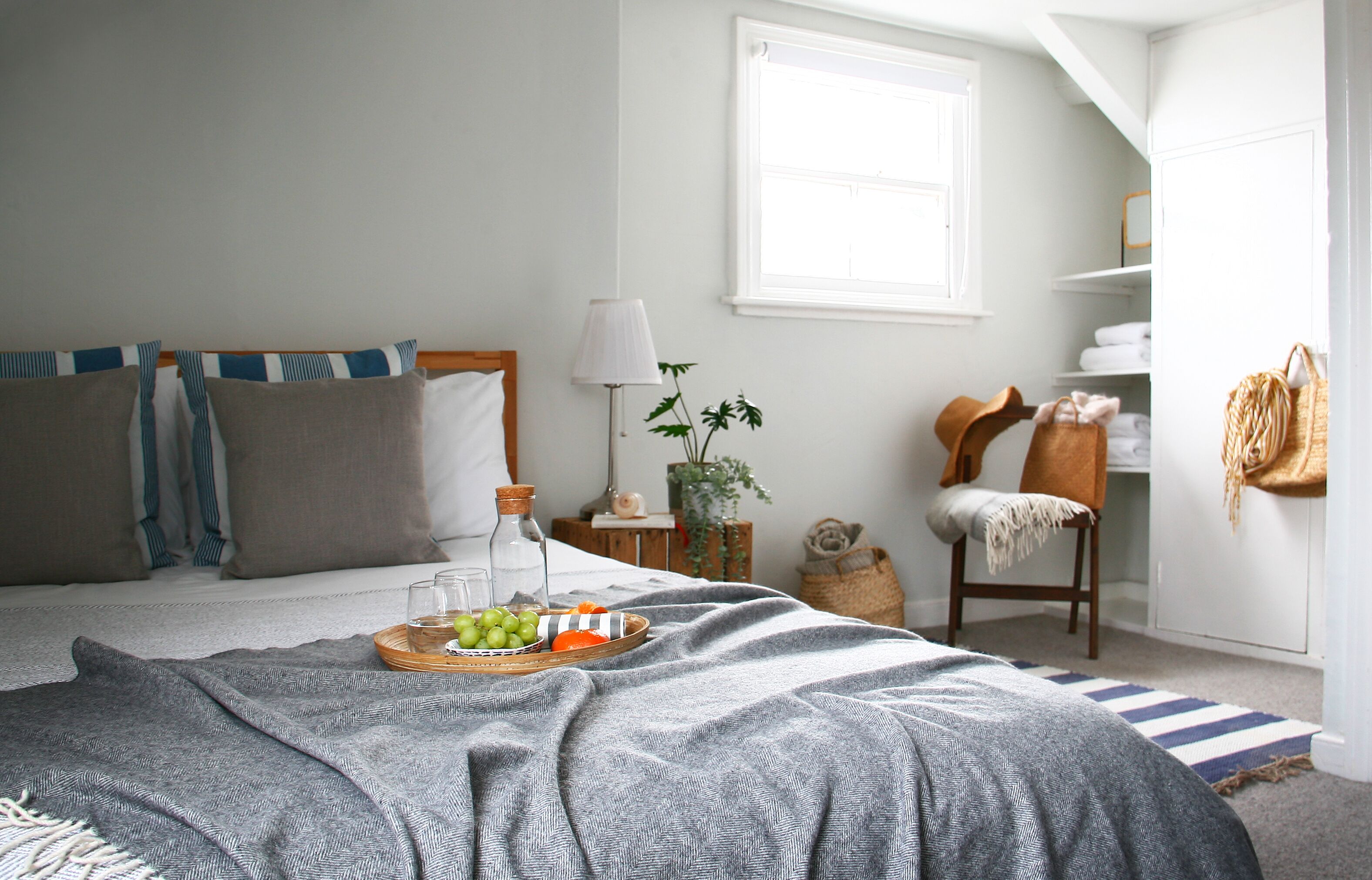 A neatly arranged bedroom with a bed, bedside table, lamp, and a window.
