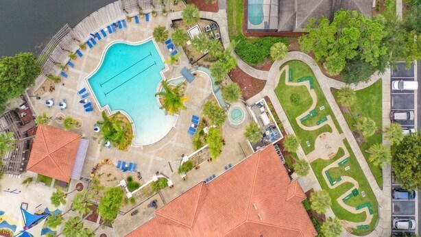 An aerial view of a resort with a large swimming pool, sun loungers, and a parking area. - Terra Verde 116 (Kissimmee)