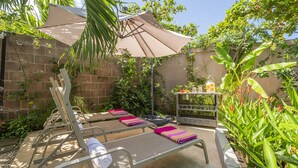 A patio with lounge chairs, a table, and a shaded area with a table and decorative items. - 55% OFF NOW Stylish 2BR Pool Retreat — Walk to Beach (Playa Langosta)