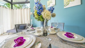 A dining table set with white plates, silverware, and a vase of flowers. - 55% OFF NOW Stylish 2BR Pool Retreat — Walk to Beach (Playa Langosta)