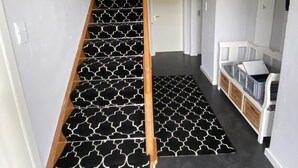 A staircase with a black and white patterned carpet leading to a landing with a white bench and storage bins. - Cozy house with garden and terrace (Espelkamp)