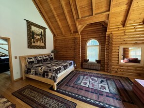 Un dormitorio tipo cabaña de madera con una cama, una ventana, un espejo y una alfombra.