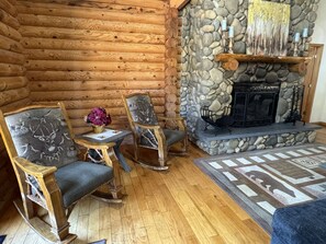 L’intérieur d’une cabane en rondins, avec une cheminée en pierre, des meubles en bois et un tapis.