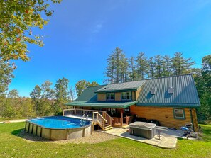 Una cabaña de troncos con piscina, mobiliario exterior y terraza cubierta.