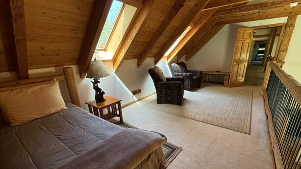 Una camera da letto con un letto, un comodino, una lampada, una sedia e vista su un corridoio.