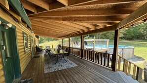Una terrazza in legno coperta con piscina, area salotto all'aperto e vista sui dintorni.