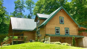 A log cabin with a metal roof, a porch, and a grassy yard. - Secluded Luxury Lodge 57 acres Hocking Hills Ohio (Logan)