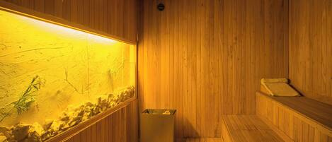 Una sauna de madera con recinto de vidrio, un banco y un cubo de basura pequeño.