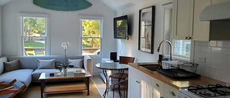 A modern kitchen with a gas stove, white cabinets, and a dining area with a table and chairs.