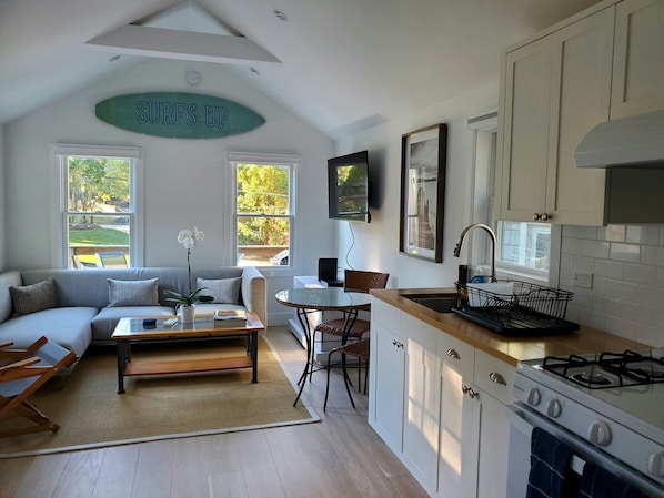 A modern kitchen with a gas stove, white cabinets, and a dining area with a table and chairs.