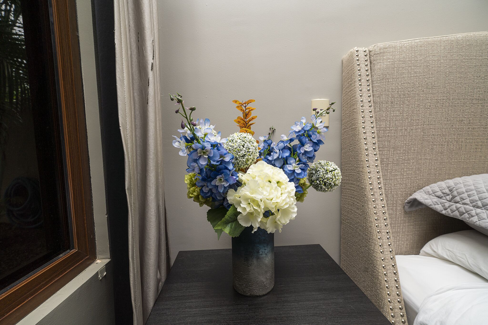 A vase with flowers on a bedside table in a hotel room.
