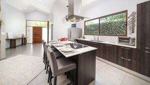Une cuisine moderne dotée d’un îlot central, de meubles en bois foncé et d’une grande fenêtre offrant une vue sur la verdure.