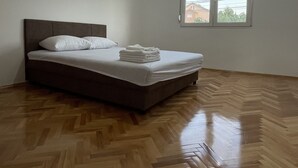 A bedroom with a bed, a window, and a wooden floor.