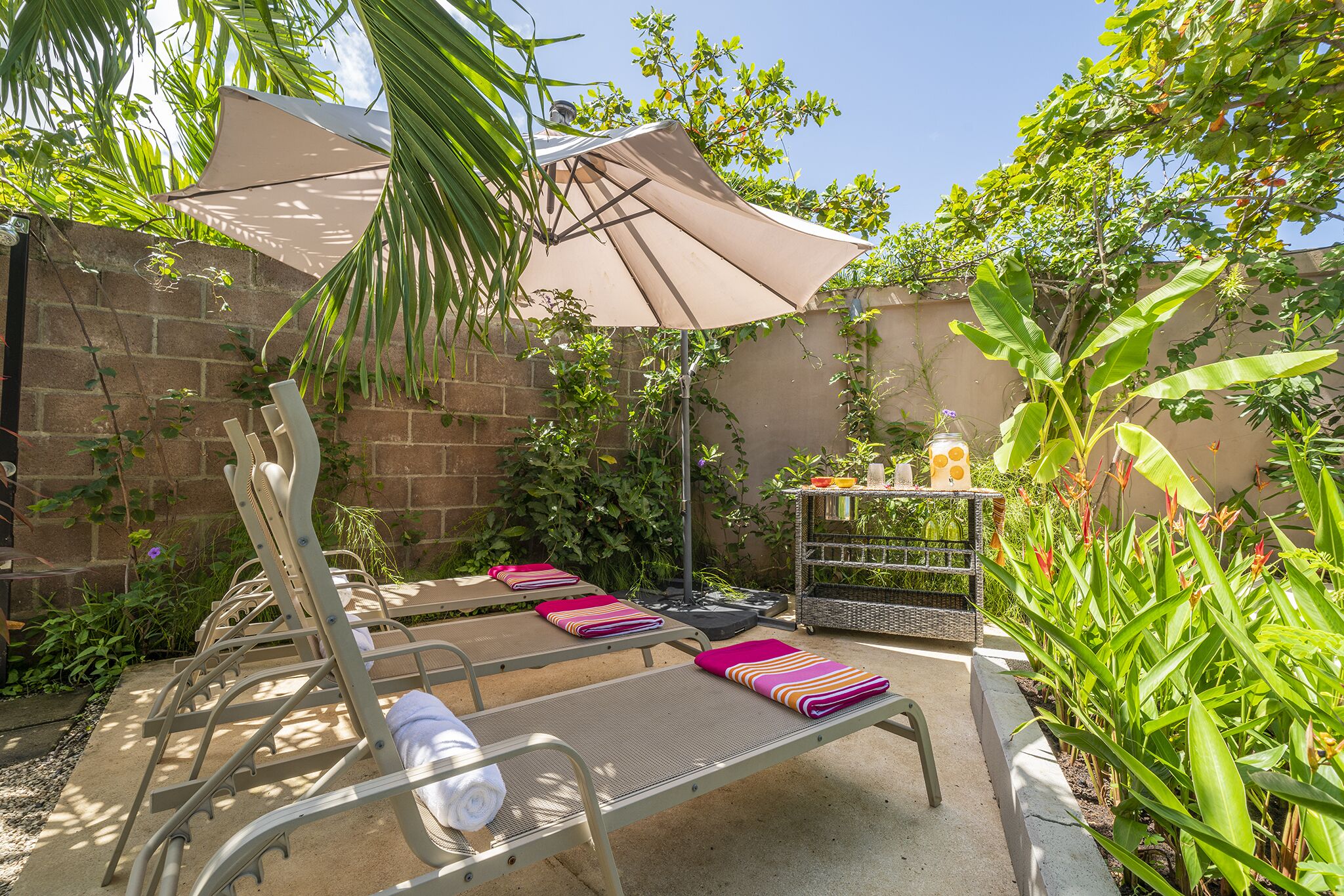 A patio with lounge chairs, a table, and a shaded area with a table and decorative items.