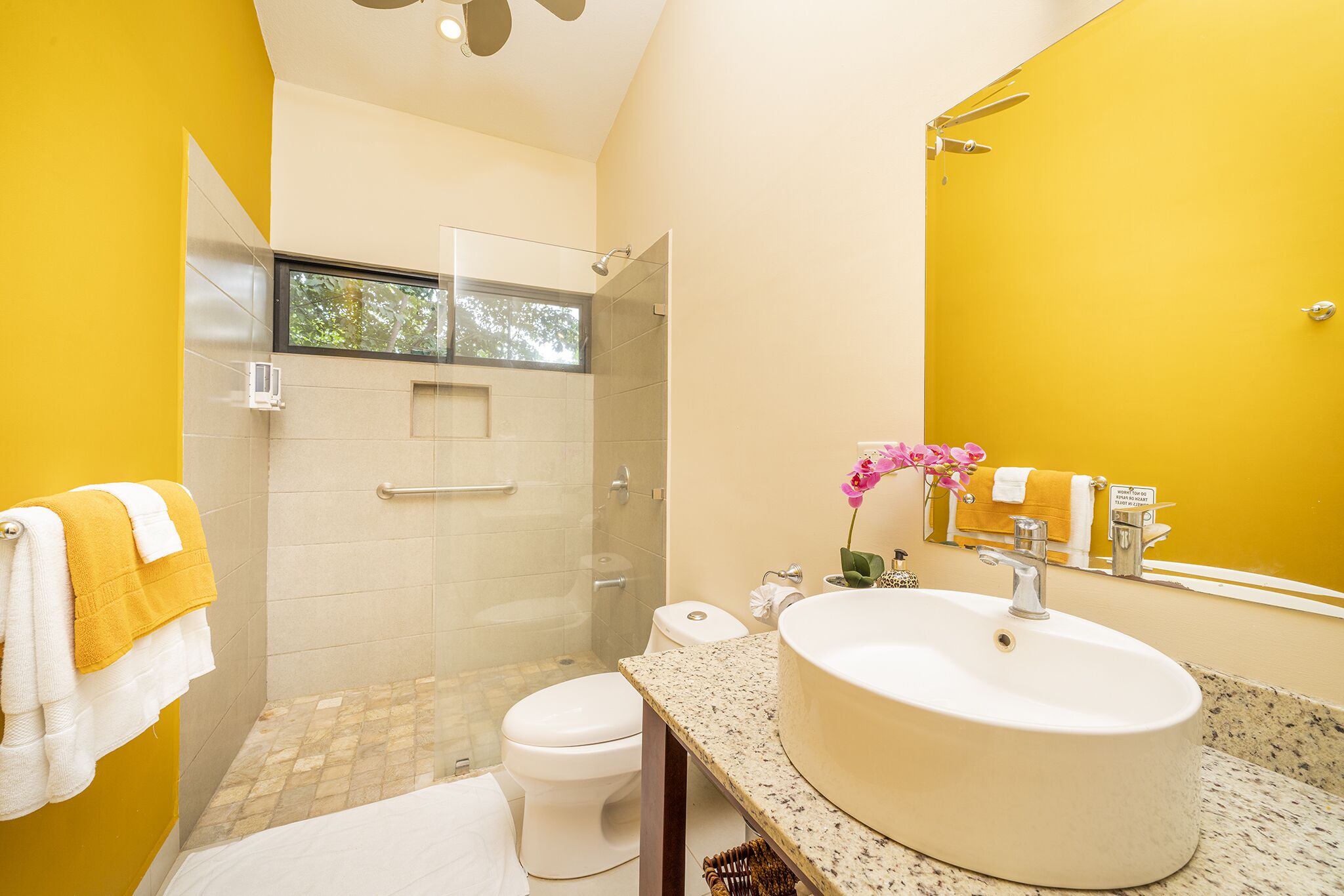 A modern bathroom with a large sink, toilet, and glass-enclosed shower.
