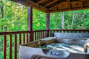 A hot tub with a control panel, surrounded by a wooden deck and a forest view. - Experience serenity near entertainment, stay at our 3-bedroom cabin, Pkwy close! (Pigeon Forge)