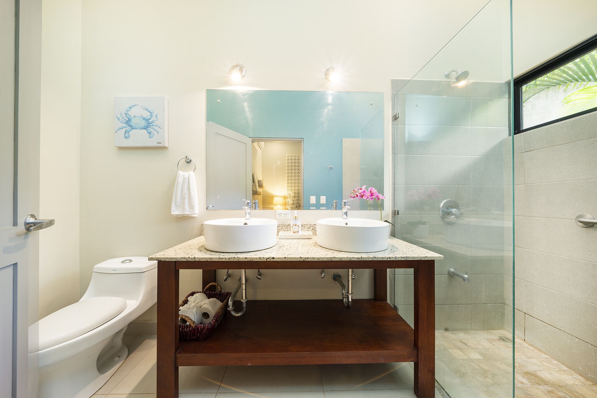 A bathroom with two sinks, a toilet, a mirror, and a shower.