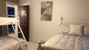 Ein Schlafzimmer mit zwei Betten, einer Leiter, einer Tür und einem an der Wand hängenden Gemälde.