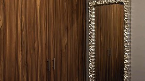 Ein Holzkleiderkasten mit Spiegel und Metallrahmen.