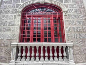 A building facade with a red window and a stone wall with a patterned design.