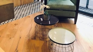 Un soggiorno moderno con una poltrona verde, un tavolino in legno e una parete decorata con motivi circolari.