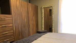 Una camera da letto con un'armadio in legno, un letto con copriletto grigio e bianco e uno specchio con cornice decorativa.