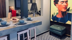 Una cucina moderna con zona pranzo, caratterizzata da un pavimento a motivi geometrici, un elettrodomestico rosso e un grande quadro astratto.