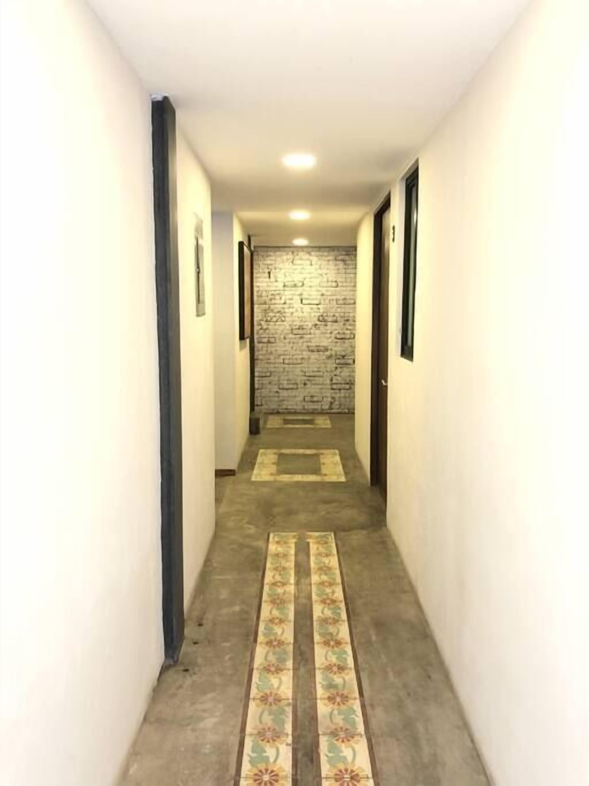 A narrow hallway with a textured wall, a carpeted floor, and a door at the end.
