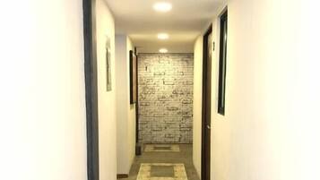 A narrow hallway with a textured wall, a carpeted floor, and a door at the end.