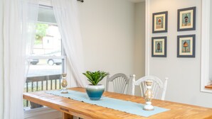 Ein Essbereich mit Holztisch, Stühlen, einem Blumentopf und gerahmten Bildern an der Wand.