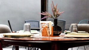 Una mesa de comedor puesta con platos, cubiertos y un florero con flores.