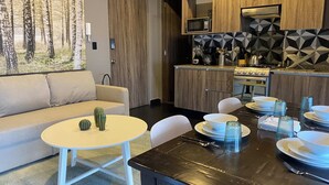 A modern kitchen with a dining area, a sofa, and a painting of a forest. - Excelente Departamento a una cuadra del Ángel (Ciudad de México)