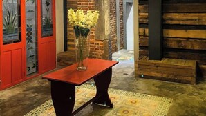 A room with a wooden wall, a neon sign, a red door, and a table with a vase of flowers. - Excelente Departamento a una cuadra del Ángel (Ciudad de México)