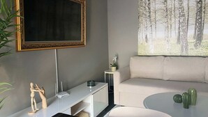 Una sala de estar moderna con un cuadro grande, un sofá, una mesa de centro y un televisor montado en la pared.