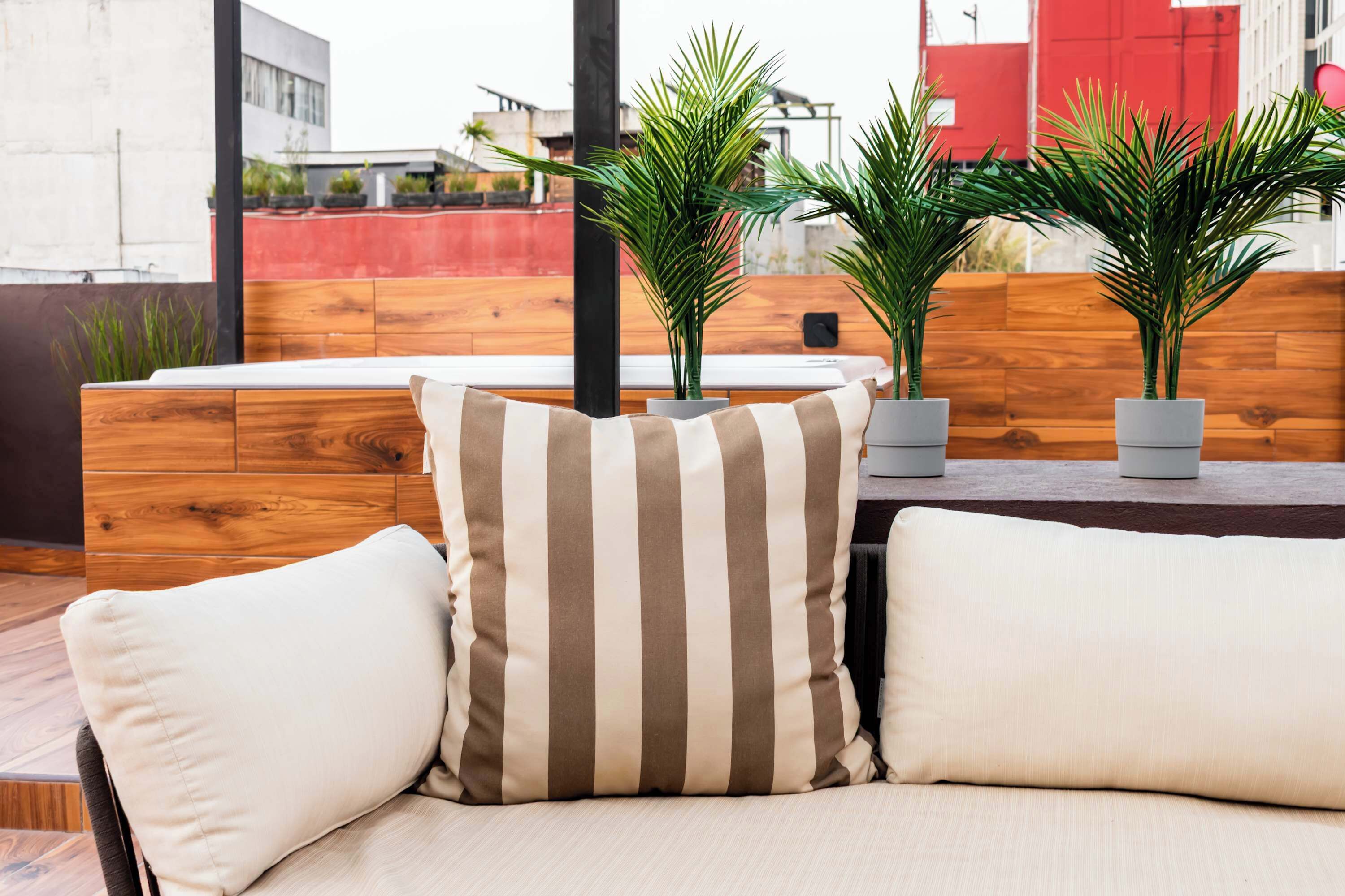 Un espace extérieur moderne, aménagé avec des bancs en bois, des coussins à rayures et des plantes en pot.