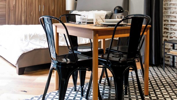 A modern hotel room with a wooden wardrobe, a dining table with chairs, a bed, and a patterned floor. - Lujoso Departamento muy Amplio en la condesa (Ciudad de México)