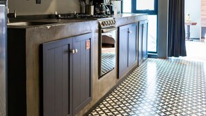 A modern kitchen with dark cabinetry, a gas stove, and a patterned floor. - Lujoso Departamento muy Amplio en la condesa (Ciudad de México)