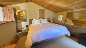 A cozy bedroom with a wooden ceiling, a large bed, a bedside table, and a window. - Beautiful view by the creek, close to Vail Village (Vail)