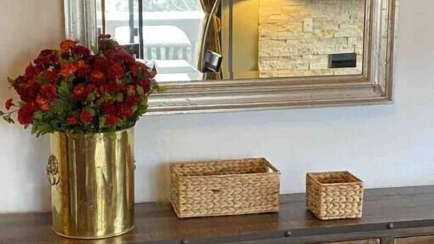 A wooden dresser with a mirror above it, a vase of red flowers, and two woven baskets. - Beautiful view by the creek, close to Vail Village (Vail)