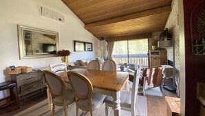 A cozy dining area with a wooden table and chairs, a fireplace, and a TV mounted on the wall. - Beautiful view by the creek, close to Vail Village (Vail)