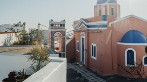 Een kerk met een klokkentoren en een koepel, omgeven door een witte muur en bloempotten.
