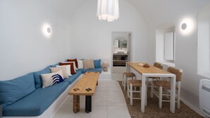 Een moderne, minimalistische woonruimte met een blauwe bank, een houten eettafel en witte muren.