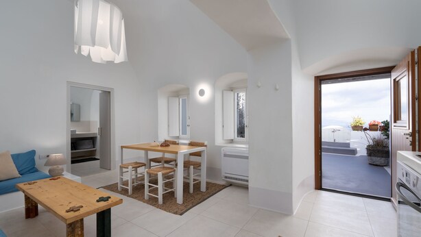 Een moderne woonkamer met een houten eettafel, witte wanden en een groot raam.